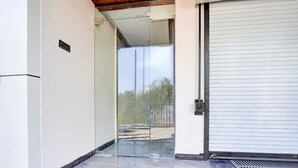 A modern building entrance with a glass door, a metal door frame, and a tiled floor. - Deluxe Hotel Shree Ganesha (Indore)