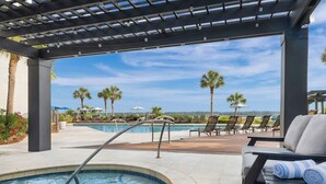 Ein Poolbereich mit Whirlpool, Liegestühlen und einer Pergola mit Beleuchtung.