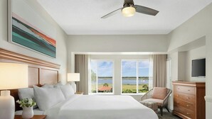 Ein Hotelzimmer mit einem großen Bett, einem Deckenventilator, einem Fernseher, Blick ins Freie und einer Holzkommode.