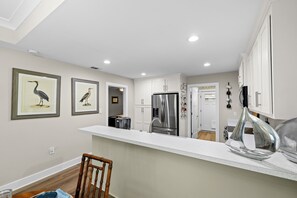 A kitchen with white cabinets, a stainless steel refrigerator, and a bar area with a unique silver sculpture. -  Dragonfly Nest Upscale Home Pensacola Beach 9 miles, Public Golf course 1 mile (Pensacola)