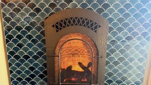 A fireplace with a decorative screen, set against a tiled wall with a scalloped pattern. - Modern 1-bedroom condo in West Seattle, with quick access to downtown (Seattle)