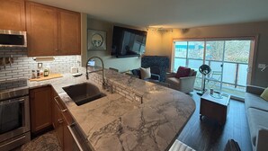 A modern kitchen with marble countertops, wooden cabinets, and a built-in oven. - Modern 1-bedroom condo in West Seattle, with quick access to downtown (Seattle)