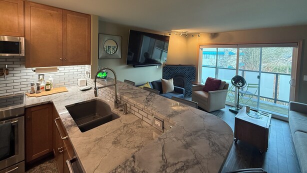A modern kitchen with a marble countertop, wooden cabinets, and a built-in oven. - Modern 1-bedroom condo in West Seattle, with quick access to downtown (Seattle)