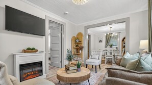 Un salon doté d’une cheminée, d’un téléviseur à écran plat, d’une table basse ronde et d’un coin salon confortable.