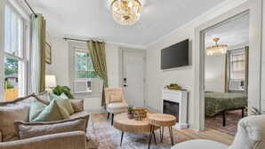 Un salon doté d’une cheminée, d’un téléviseur fixé au mur et d’un lustre.