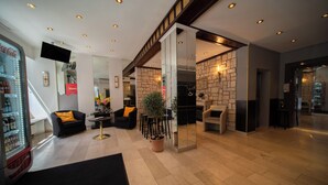 A modern lobby with seating, a vending machine, and a staircase. - Hotel Mondial Munich (Munich)