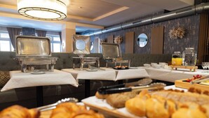A buffet setup with various food items and serving equipment. - Hotel Mondial Munich (Munich)