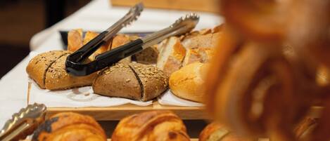 Ein reichhaltiges Buffet mit verschiedenen Backwaren, darunter Croissants und Brötchen.