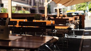 Outdoor seating with tables and chairs, umbrellas, and a street view in the background. - Hotel Mondial Munich (Munich)