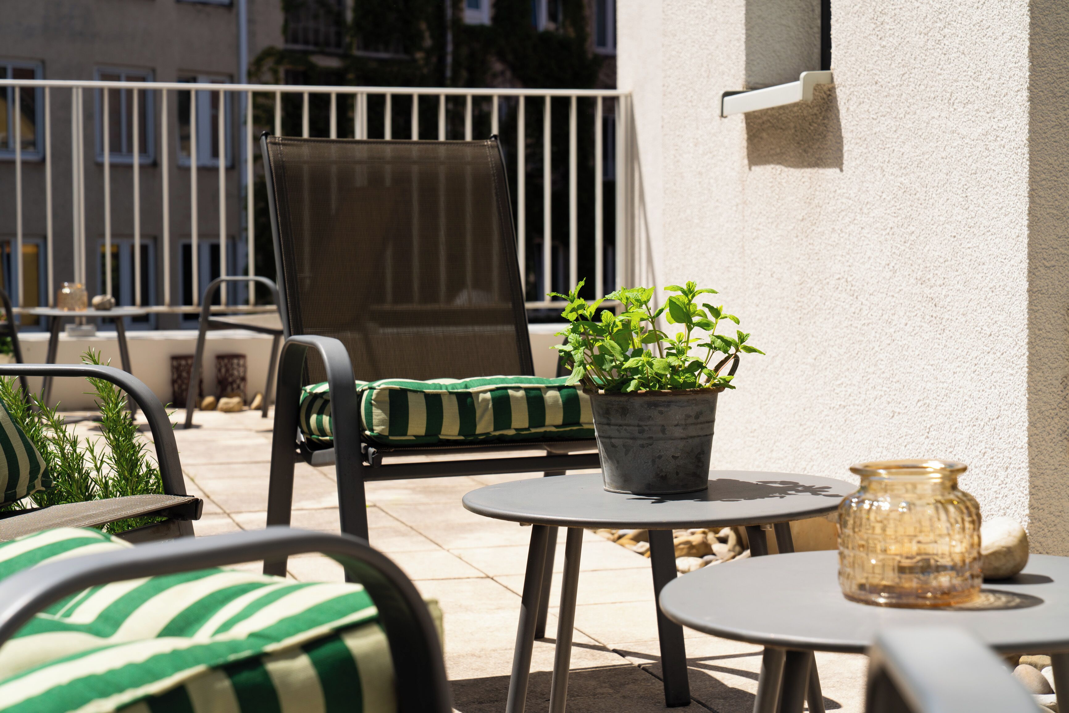 An outdoor seating area with chairs, a table, a potted plant, and a decorative jar.
