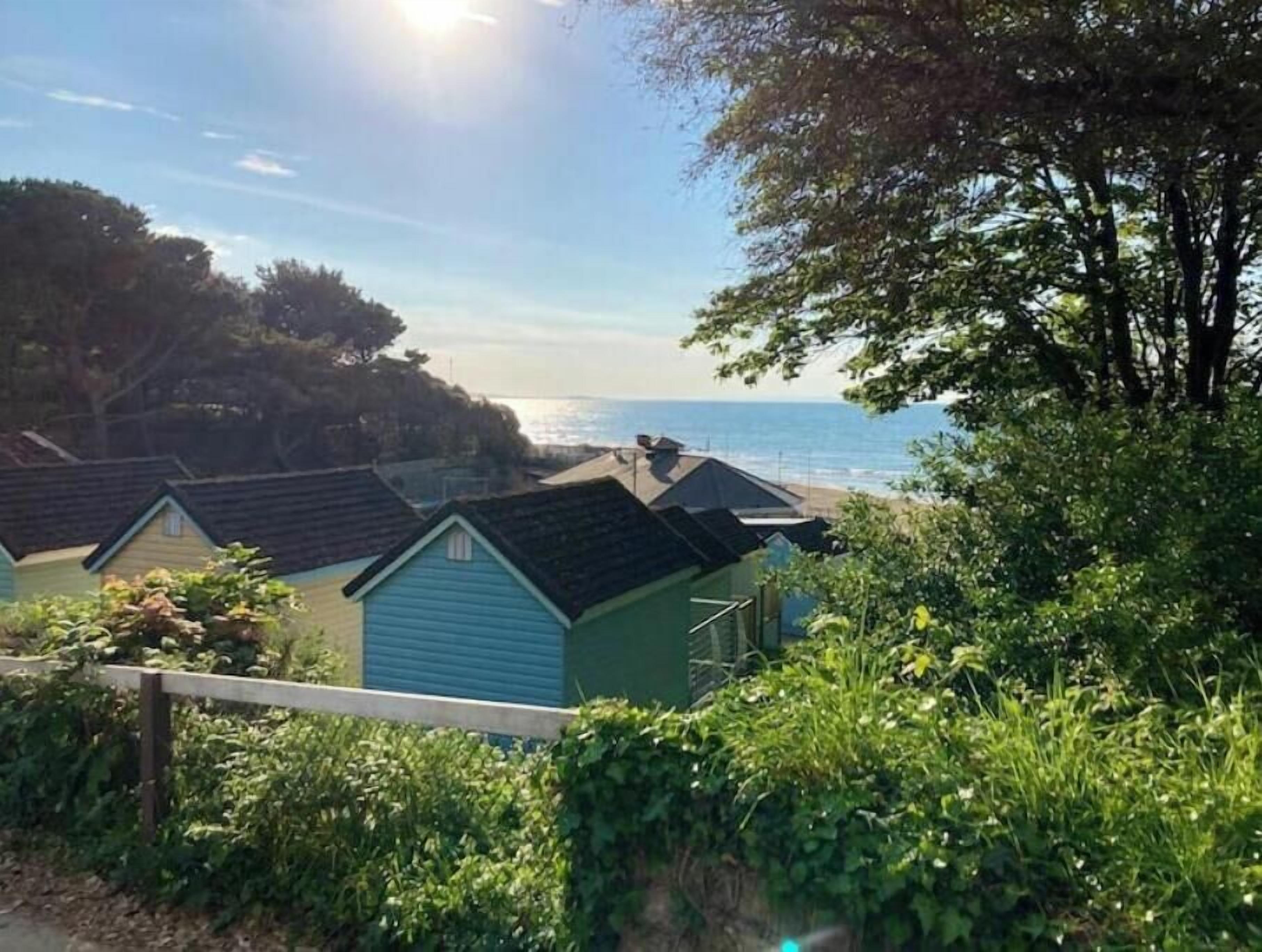 Blick auf die Küste mit Strandhäusern und blauem Himmel.