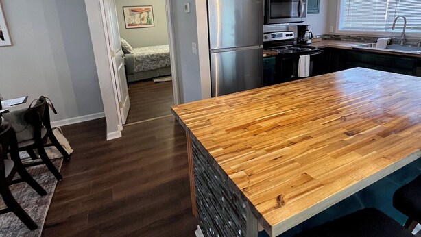 A modern kitchen with a central island, stainless steel appliances, and a dining area with a wooden table and chairs.