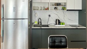 Una cocina con un refrigerador de acero inoxidable, una mesa de comedor de madera y una silla negra.