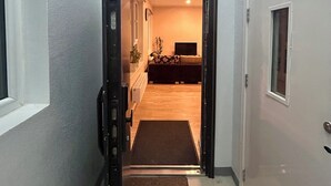 Un pasillo que conduce a una sala de estar con un sofá y una planta.