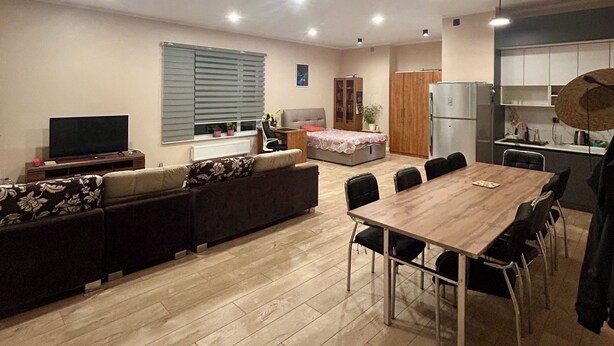 Una sala de estar moderna con sofá, televisor, mesa de comedor y sillas.