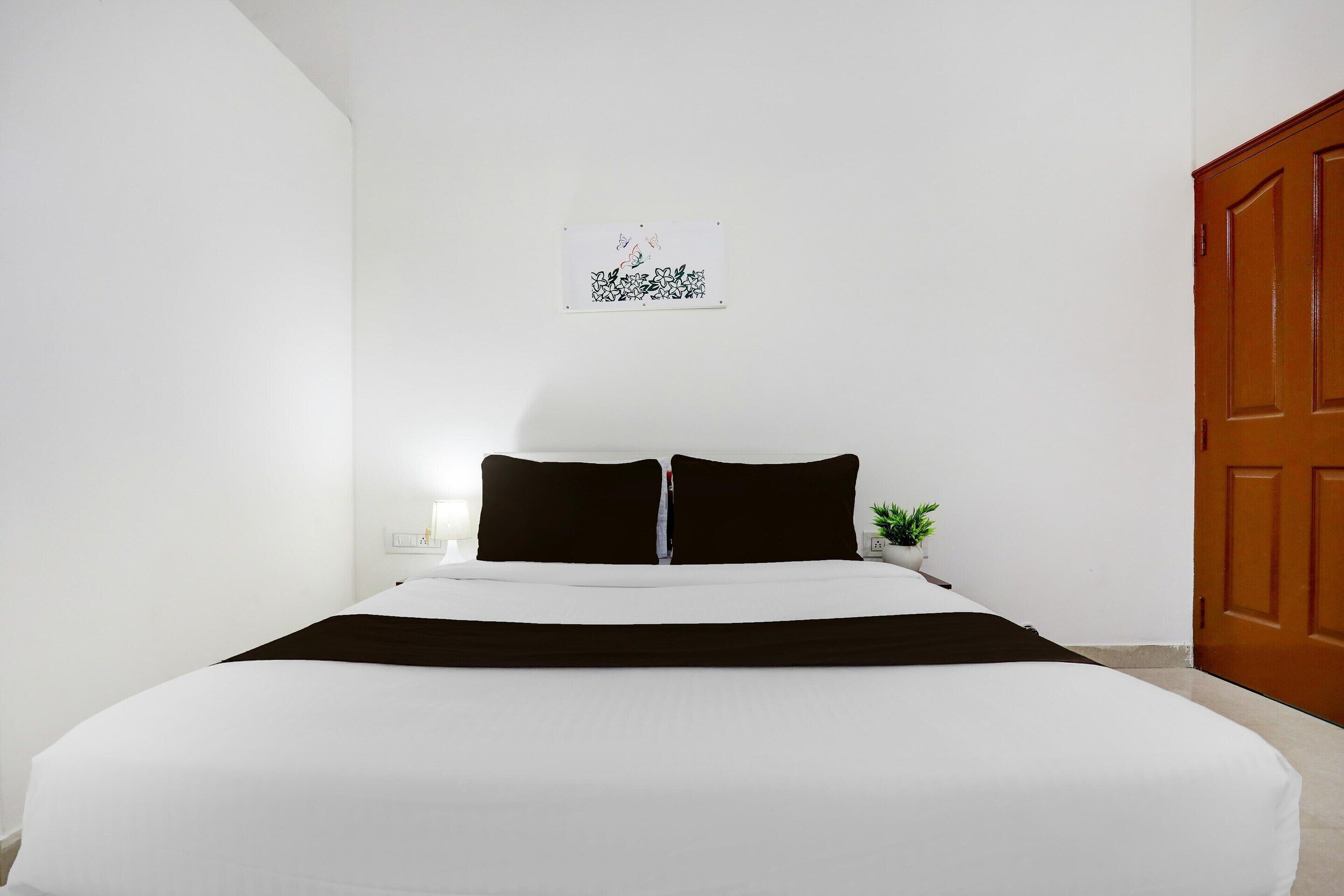 Ein Schlafzimmer mit Bett, Nachttisch, Wandbild und Tür.