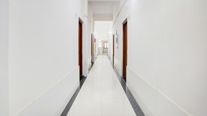 A long, narrow hallway with white walls and a tiled floor, leading to a door at the end. - Deluxe Sri Krishna Nilaya (Bengaluru)
