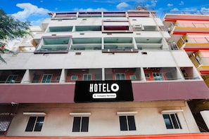 A multi-story hotel with balconies, a sign indicating it is company-serviced, and a clear blue sky. - Deluxe Sri Krishna Nilaya (Bengaluru)