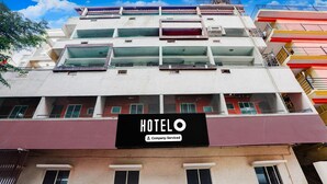 A multi-story hotel with balconies, a 'HOTELO' sign, and a company-serviced label. - Deluxe Sri Krishna Nilaya (Bengaluru)