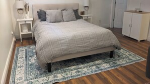 Ein Schlafzimmer mit Bett, Nachttischen, einem Schminktisch und einer Tür.