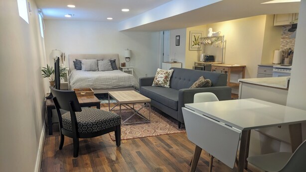 Ein modernes Wohnzimmer mit Sofa, Esstisch, Couchtisch und einem Küchenbereich im Hintergrund.
