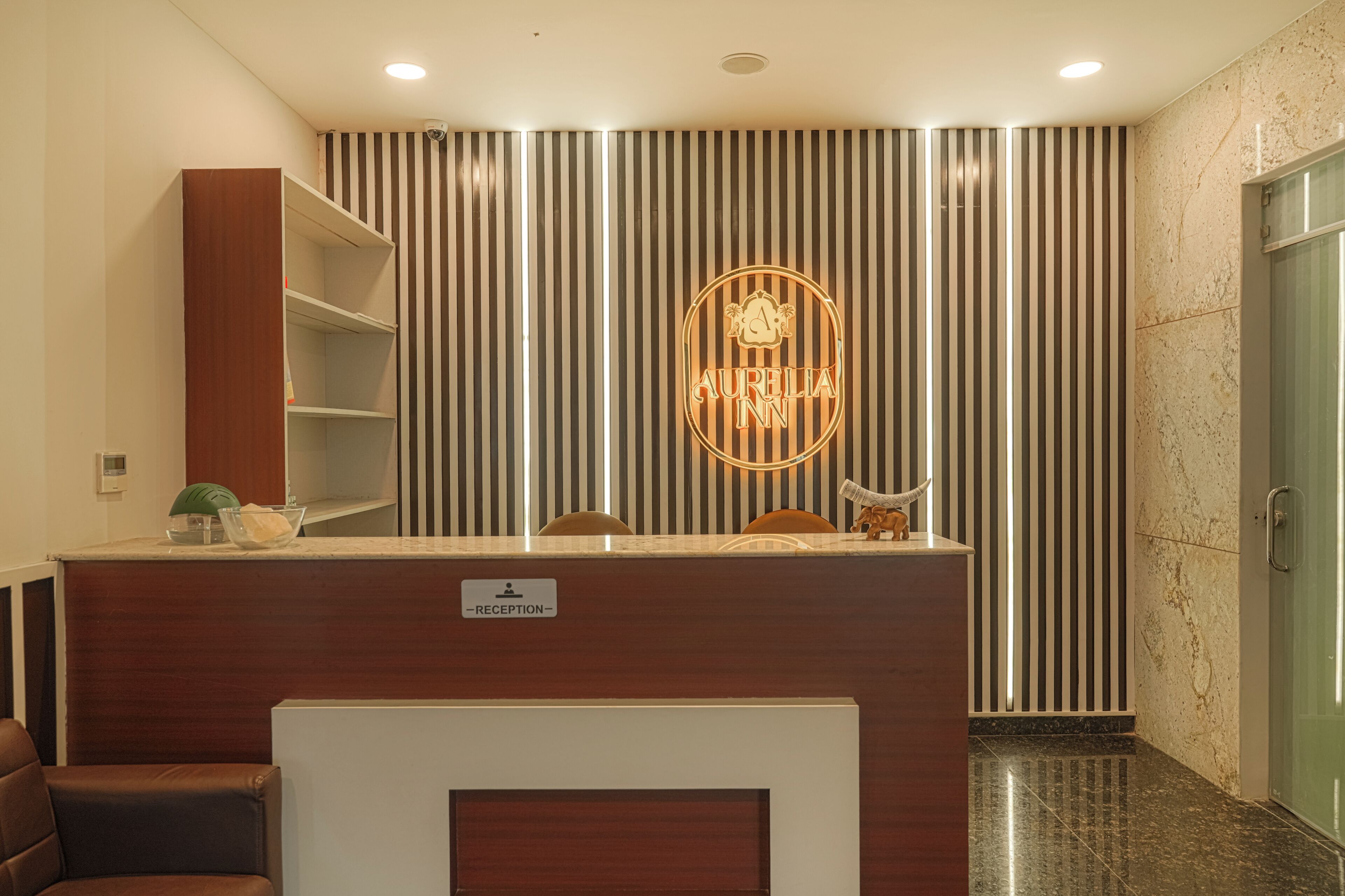 A reception desk with a sign indicating 'RECEPTION,' a reception area with striped wall panels, and a reception counter with a neon sign.