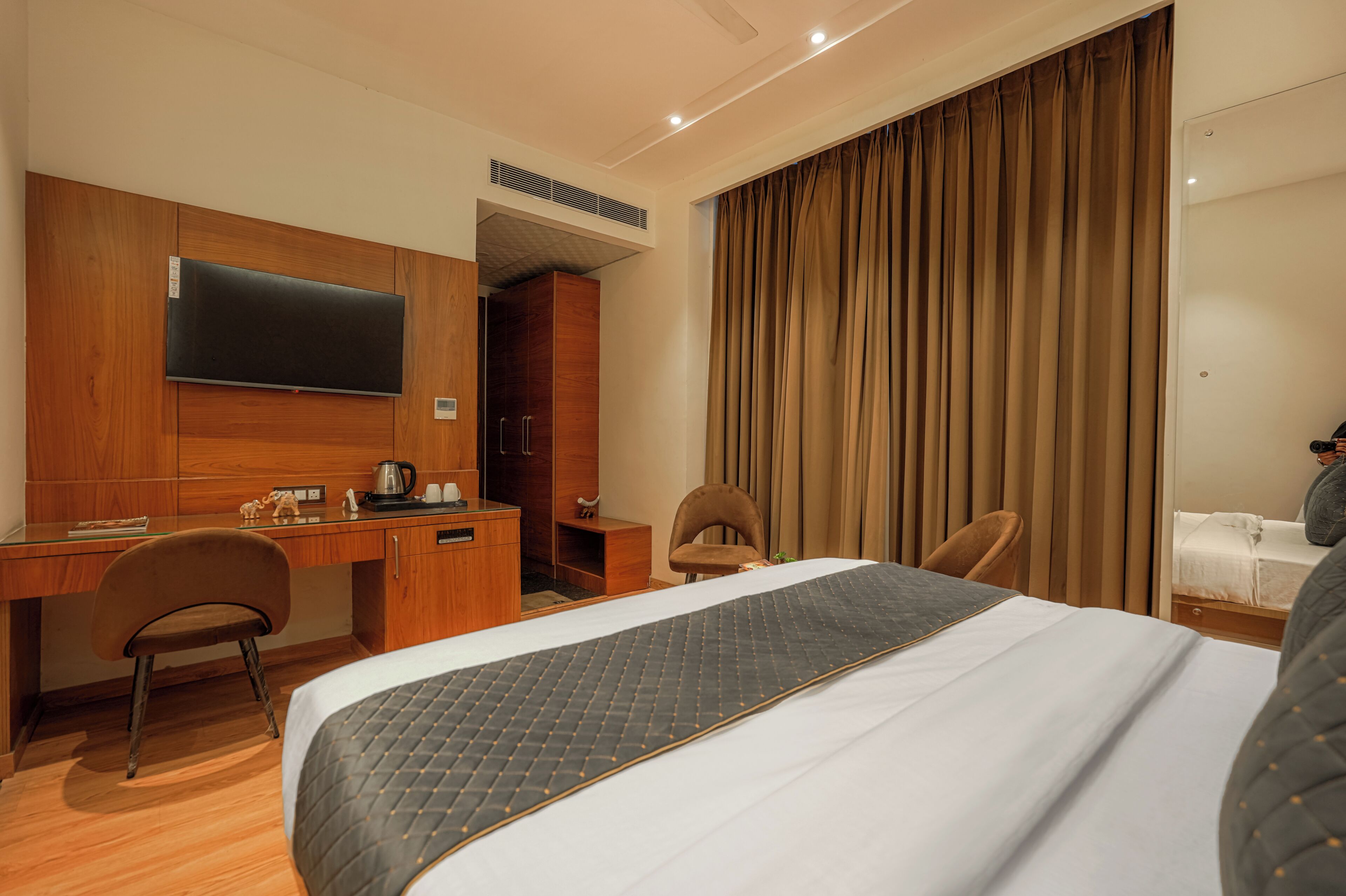 Een hotelkamer met een bed, een bureau, een stoel, een televisietoestel en een kledingkast.