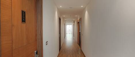A hallway with wooden doors, recessed lighting, and a wooden floor.