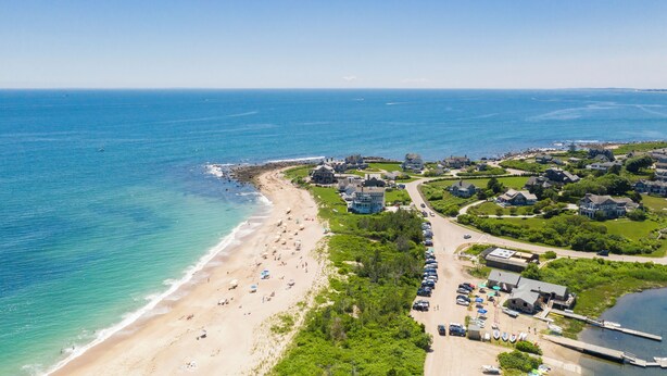 An aerial view of a coastal town with a beach, houses, and parked cars. - Exceptional location with both Weekapaug Beaches and Quonnie Salt Pond Access (Charlestown)