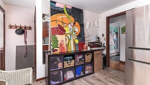 A kitchen with a large painting, a refrigerator, and a wicker basket. - Exceptional location with both Weekapaug Beaches and Quonnie Salt Pond Access (Charlestown)