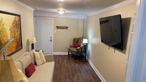 A living room with a sofa, a chair, a TV, and a painting on the wall. - FIFA FANS STAY HERE! Excellent location minutes from Atlanta Airport and STADIUM (atlanta)