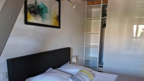 Une chambre à coucher avec un lit, une table de chevet et un tableau accroché au mur.