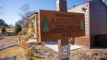 A wooden sign with 'Welcome to AMELIA'S HIDDEN HIDEAWAY EST. 2021' and a QR code.