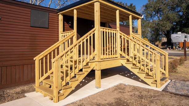 A wooden staircase leading to a covered porch of a cabin with a metal roof. - Amelia's Hidden Hideaway/ quiet cottage located in Broussard, La. (Broussard)