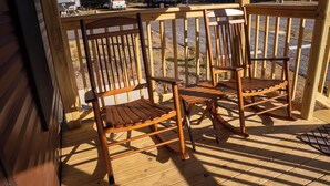 A wooden deck with two rocking chairs and a view of a parking lot with RVs. - Amelia's Hidden Hideaway/ quiet cottage located in Broussard, La. (Broussard)