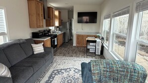 A modern living room with a gray sofa, a blue armchair, a patterned rug, and a ceiling fan.
