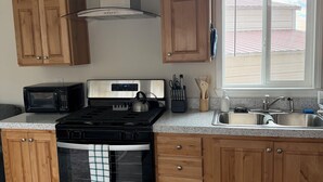 A kitchen with wooden cabinets, a stainless steel stove, a microwave, and a window with a view.
