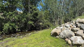 A natural landscape with a grassy area, a small stream, and a pile of rocks.