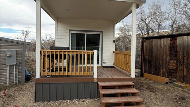 A covered outdoor area with a wooden deck, a sliding door, and a small porch.