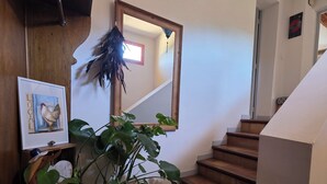 Eine Treppe mit Holzbeschlägen, ein Blumentopf, ein gerahmtes Bild und ein dekorativer Gegenstand an der Wand.