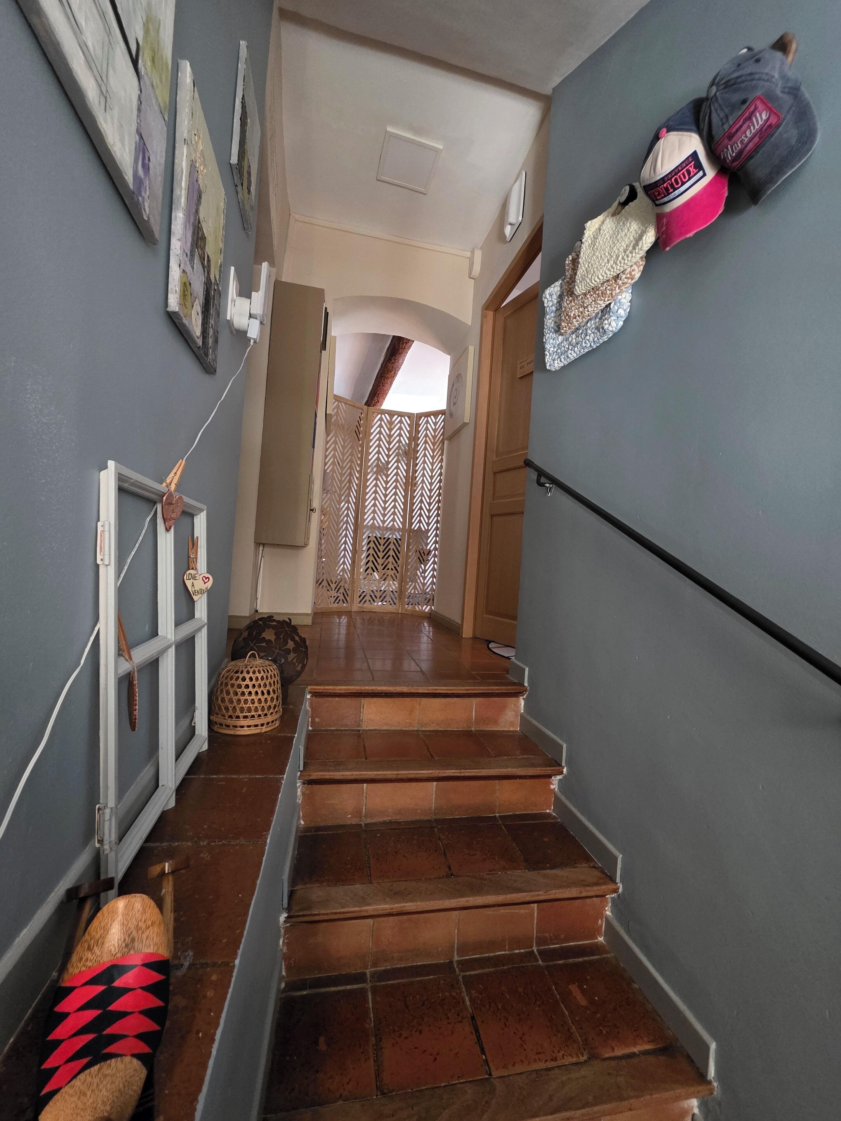 A staircase leading to a room with a view, a door with a decorative screen, and a wall with a hanging bag.