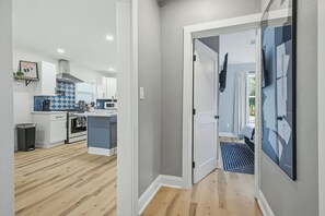A modern kitchen with white cabinets, a blue backsplash, and a stainless steel range hood. - Graffiti Blues. Fun 2BR Near Downtown. Snookball + Firepit (Pensacola)