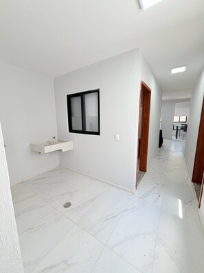 A spacious room with a marble floor, a built-in sink, and a window with black framing.