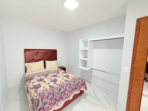 A bedroom with a bed, a nightstand, a wardrobe, and a ceiling light.