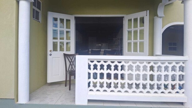 Een kamer met een wit balkon, een deur en een raam met uitzicht.