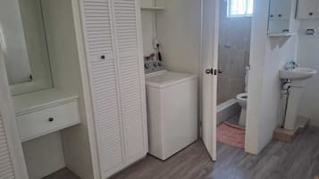 Une petite salle de bain équipée d’un lave-linge, de toilettes et d’un lavabo.