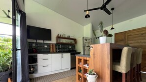 A modern kitchen with white cabinets, a wooden island, and a dining area with chairs. - Stunning 2BR Home with Fast WiFi & AC – Mountain Views & Lush Nature, Ojochal (Puntarenas Province)