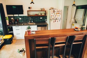 A kitchen with a wooden countertop, a sink, a refrigerator, and a television mounted on the wall. - Stunning 2BR Home with Fast WiFi & AC – Mountain Views & Lush Nature, Ojochal (Puntarenas Province)