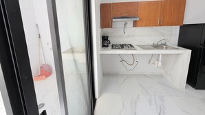 A compact kitchen with a gas stove, coffee maker, and a sink. - Residencia Gran Coyula Orange 510A (Tonala)
