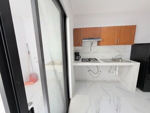 Une cuisine compacte équipée d’une cuisinière à gaz, d’une machine à café et d’un évier.